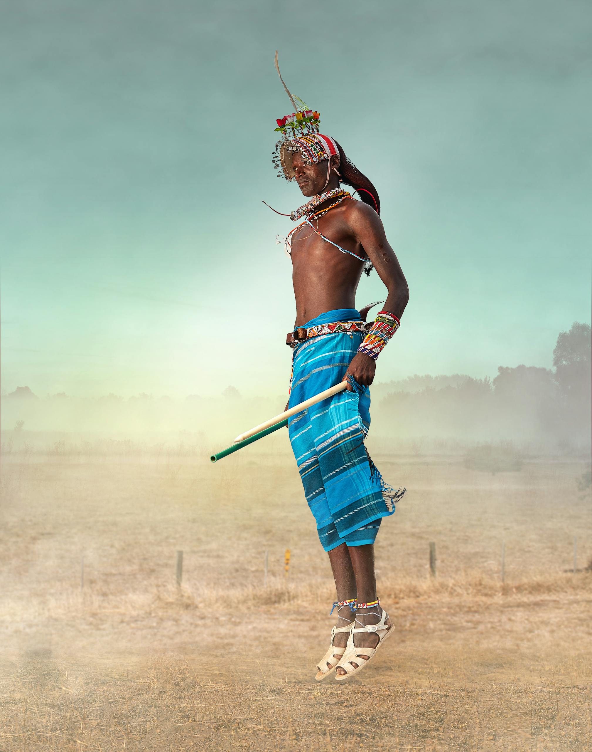 A Maasai warrior in traditional attire jumps high, showcasing cultural dance in Kenya.