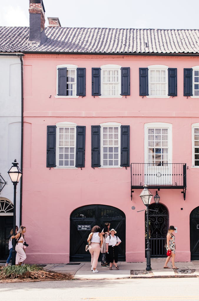 Group walking by a charming pink building in Charleston's historic district. Iconic and colorful street view.