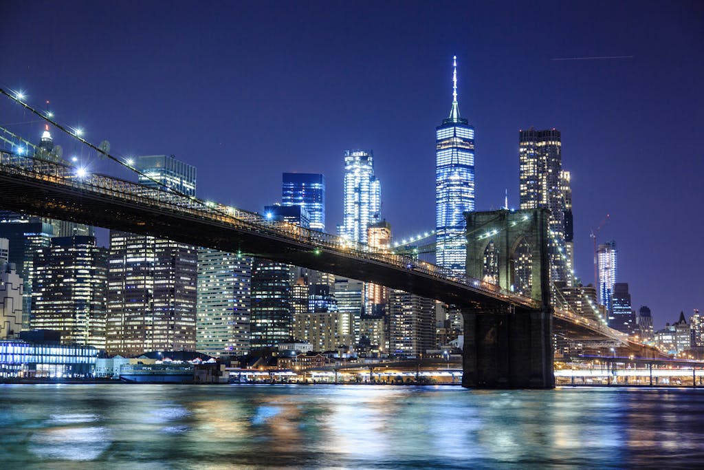 Stunning view of the Brooklyn Bridge and New York City skyline illuminated at night.