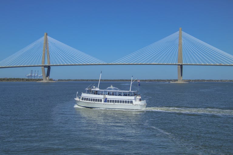 White ferry boat sails near Arthur Ravenel Jr. Bridge in Charleston.