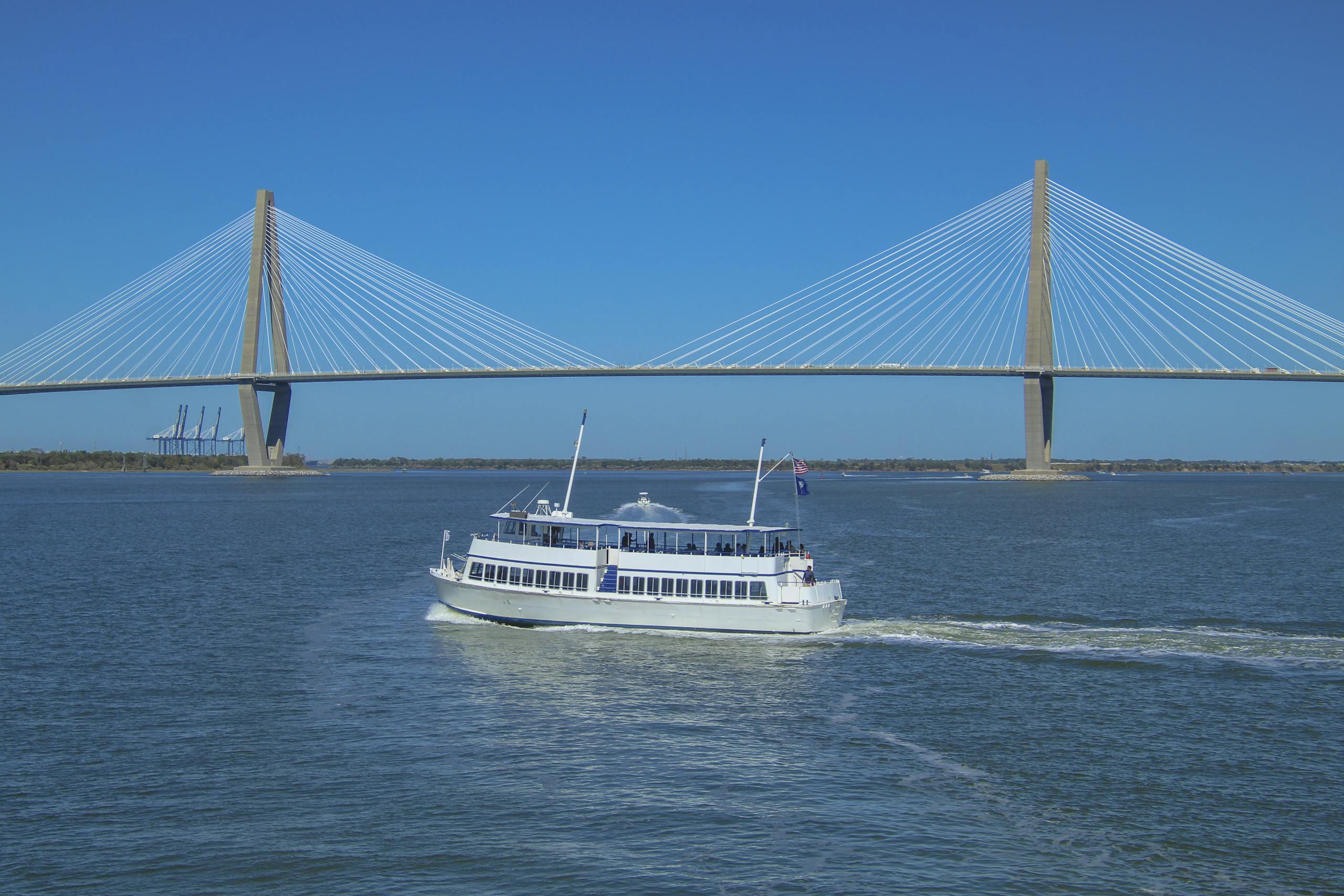 White ferry boat sails near Arthur Ravenel Jr. Bridge in Charleston.